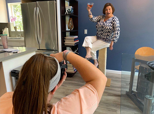 A woman getting her picture taking while holding a drink up