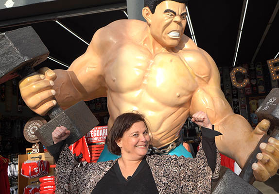 A woman flexing in front of the Venice beach Muscle Man